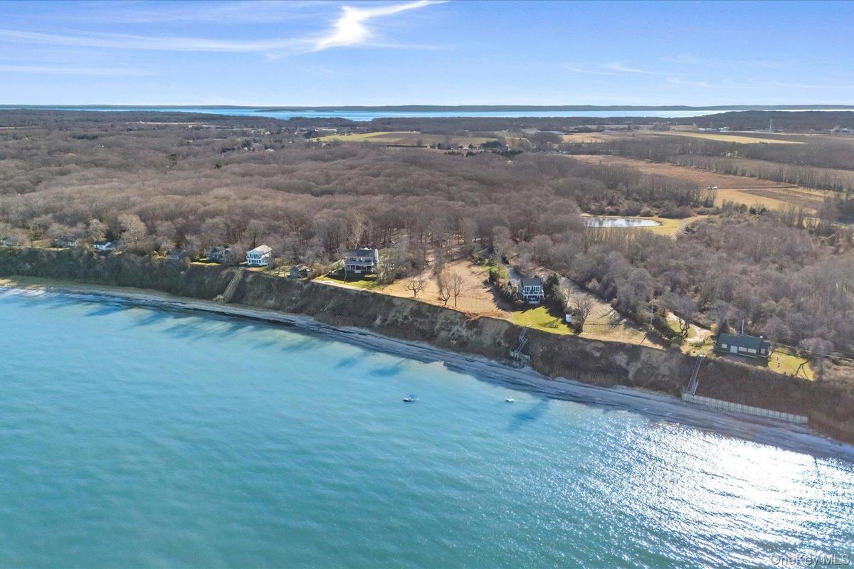 Wide aerial perspective of the North Fork shoreline, showcasing the property’s waterfront setting along the bluff, neighboring homes, and expansive op