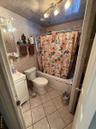 Bathroom featuring vanity, shower / bath combo with shower curtain, and tile walls