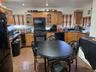 Kitchen with glass insert cabinets, dark stone countertops, black appliances, ornamental molding, and recessed lighting