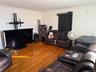 Living area with wood finished floors, crown molding, and electric panel