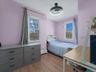 Bedroom with multiple windows, light wood-style floors, and a baseboard radiator