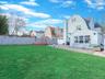 Back of property with a gambrel roof, a patio, roof with shingles, and a residential view