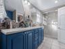 Bathroom with double vanity, light tile patterned floors, a shower stall, tile walls, and backsplash