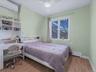 Bedroom with a wall mounted air conditioner, light wood-style floors, a baseboard radiator, ceiling fan, and an office area