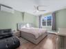 Bedroom with a wall unit AC, wood finished floors, ceiling fan, and a baseboard heating unit