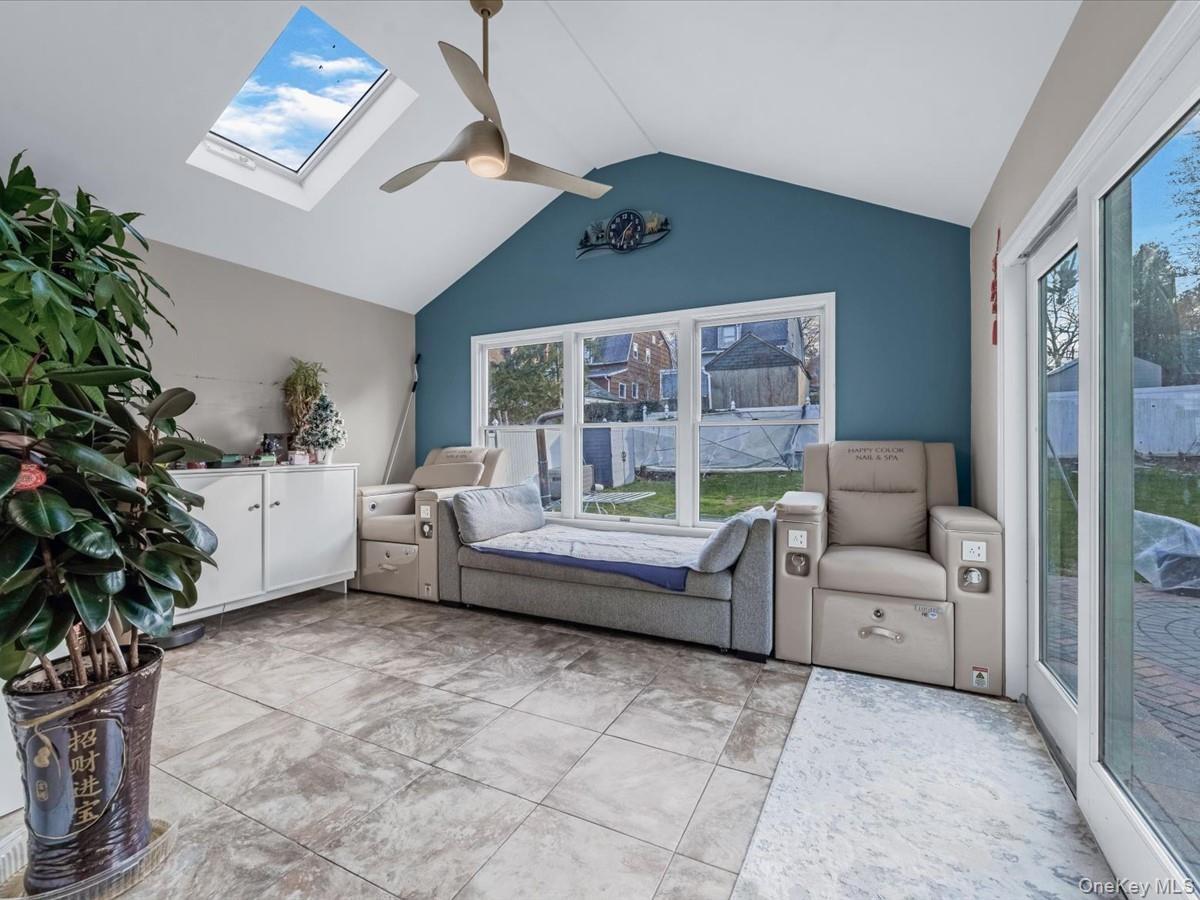 Bedroom featuring a skylight, access to exterior, lofted ceiling, and ceiling fan