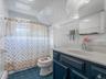 Bathroom featuring tile walls, curtained shower, vanity, dark tile patterned flooring, and a baseboard heating unit