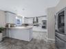 Kitchen with appliances with stainless steel finishes, light stone countertops, pendant lighting, white cabinetry, and a peninsula