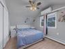 Bedroom with vaulted ceiling, a wall mounted air conditioner, light wood-style flooring, a baseboard heating unit, and a ceiling fan