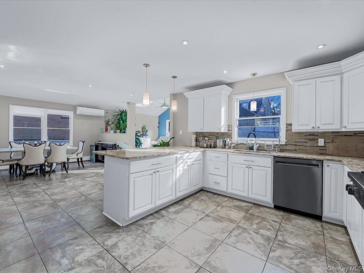 Kitchen with light stone counters, dishwasher, decorative light fixtures, white cabinets, and recessed lighting