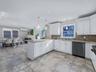 Kitchen with light stone counters, dishwasher, decorative light fixtures, white cabinets, and recessed lighting