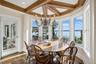 Dining space with a water view, beamed ceiling, dark wood finished floors, coffered ceiling, and a chandelier
