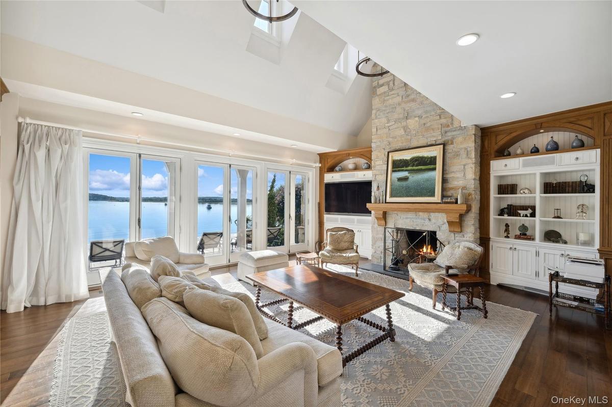 Living area with built in features, a stone fireplace, dark wood-type flooring, high vaulted ceiling, and recessed lighting