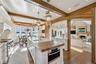 Kitchen featuring butcher block counters, decorative light fixtures, a kitchen island with sink, white cabinetry, and appliances with stainless steel 