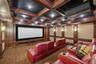 Carpeted cinema room with a decorative wall, coffered ceiling, ornamental molding, and beamed ceiling