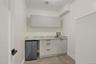 Bar featuring stainless steel refrigerator, light stone countertops, and light wood finished floors