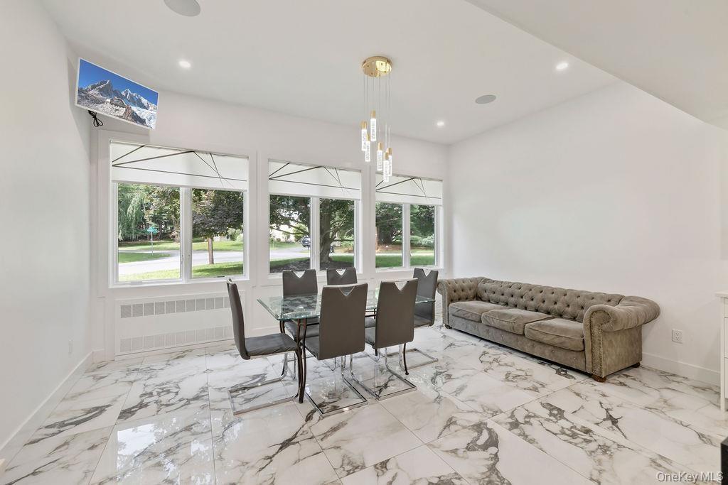 Dining room with radiator heating unit, light marble finish flooring, and recessed lighting