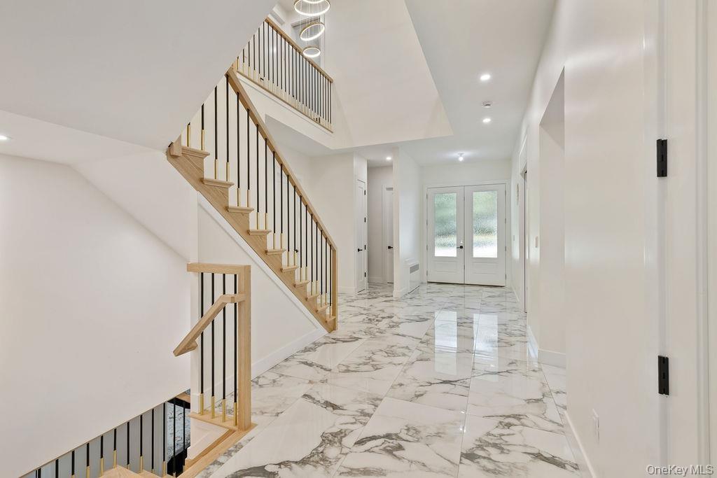 Entrance foyer with recessed lighting, stairs, french doors, and light marble finish floors