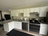 Kitchen with stainless steel appliances, white cabinets, a peninsula, and under cabinet range hood