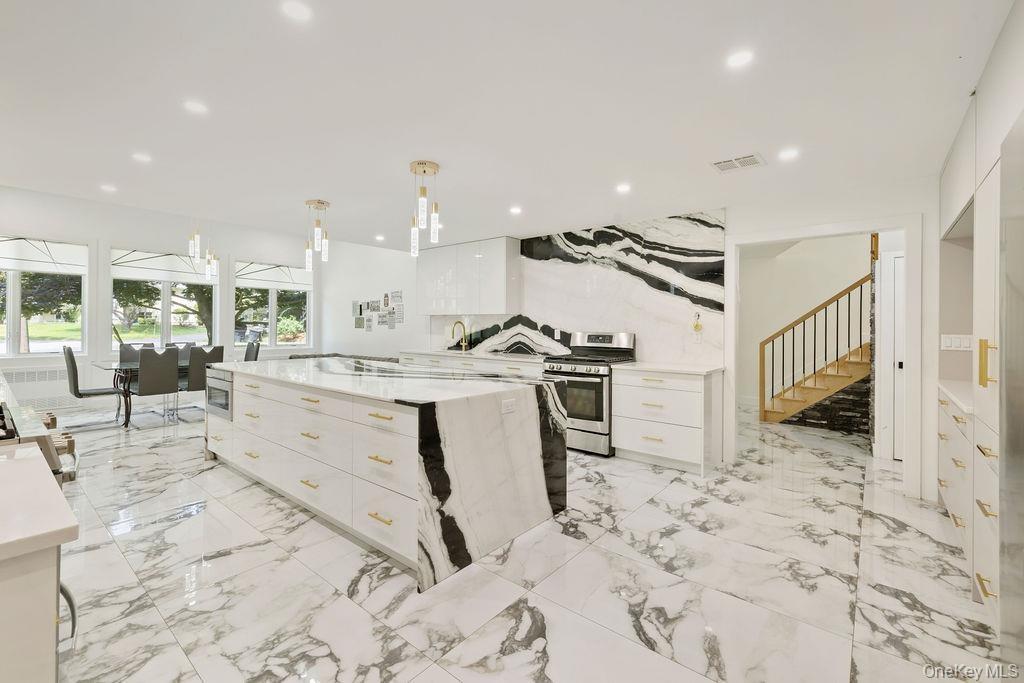 Kitchen with white cabinets, light stone countertops, stainless steel gas range oven, pendant lighting, and recessed lighting