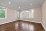 Empty room with dark wood-type flooring, ornamental molding, healthy amount of natural light, and recessed lighting