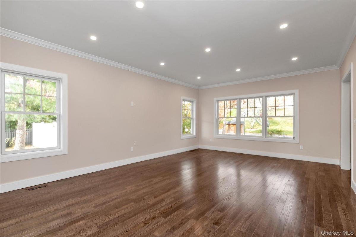 Spare room featuring dark wood-style flooring, crown molding, recessed lighting, and plenty of natural light