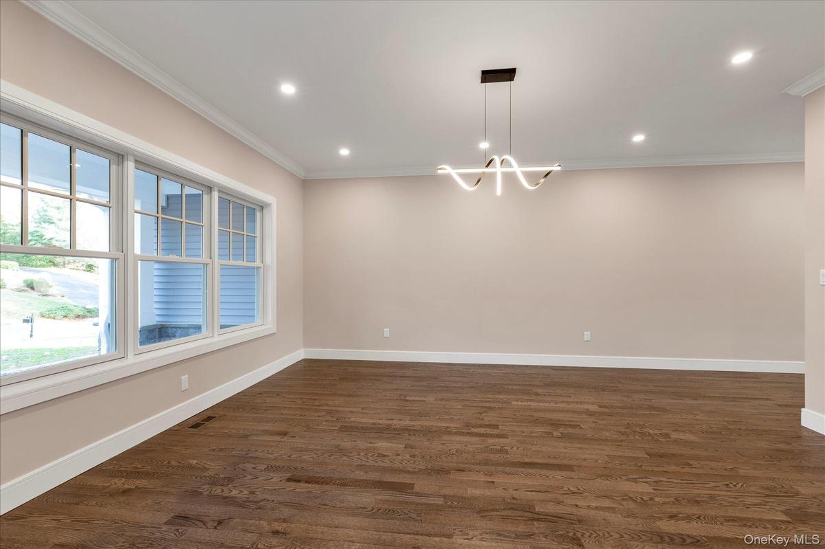 Unfurnished room with dark wood-type flooring, crown molding, recessed lighting, and a chandelier