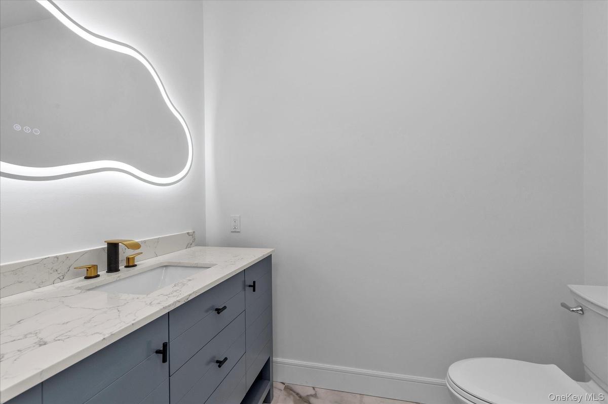 Half bath with vanity and light marble finish flooring