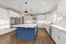 Kitchen with blue cabinets, crown molding, decorative backsplash, pendant lighting, and appliances with stainless steel finishes