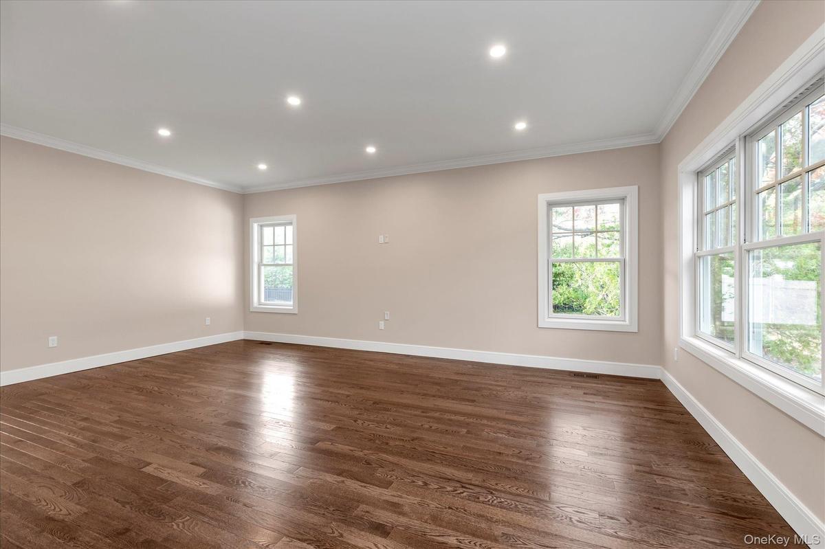 Empty room featuring dark wood finished floors, recessed lighting, and ornamental molding