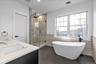 Bathroom with a freestanding bath, double vanity, a stall shower, tile walls, and dark tile patterned flooring