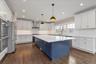 Kitchen with blue cabinetry, hanging light fixtures, ornamental molding, white cabinetry, and stainless steel appliances