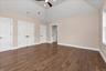 Unfurnished bedroom featuring dark wood-style floors, two closets, high vaulted ceiling, and a ceiling fan