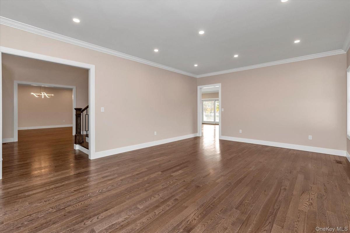 Spare room with a chandelier, recessed lighting, dark wood-style flooring, stairway, and crown molding