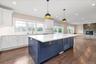 Kitchen with blue cabinetry, white cabinets, crown molding, open floor plan, and light stone countertops