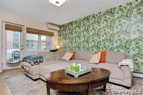 Living room featuring wallpapered walls, an AC wall unit, and wood finished floors