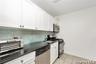 Kitchen with dark countertops, white cabinetry, appliances with stainless steel finishes, light tile patterned flooring, and backsplash