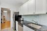Kitchen featuring white cabinets, tasteful backsplash, stainless steel appliances, light tile patterned floors, and dark stone countertops