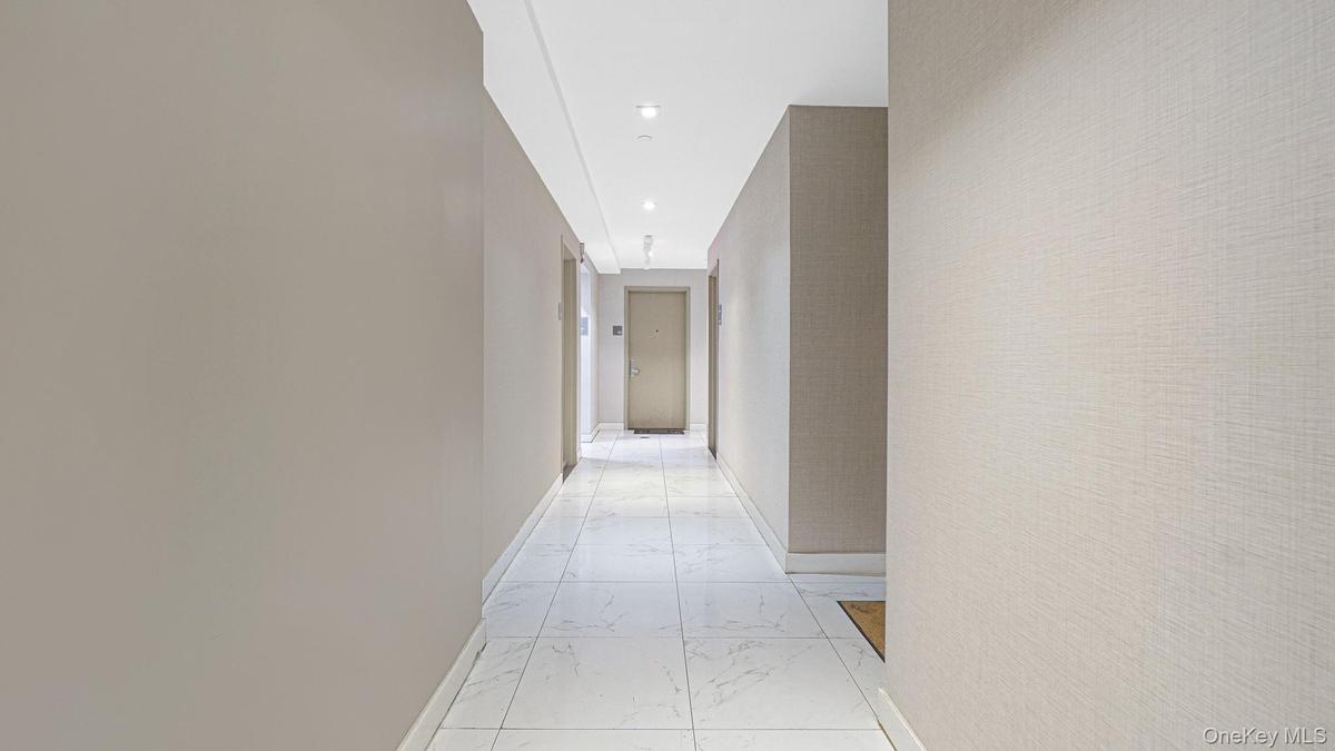 Hallway featuring light marble finish floors and recessed lighting