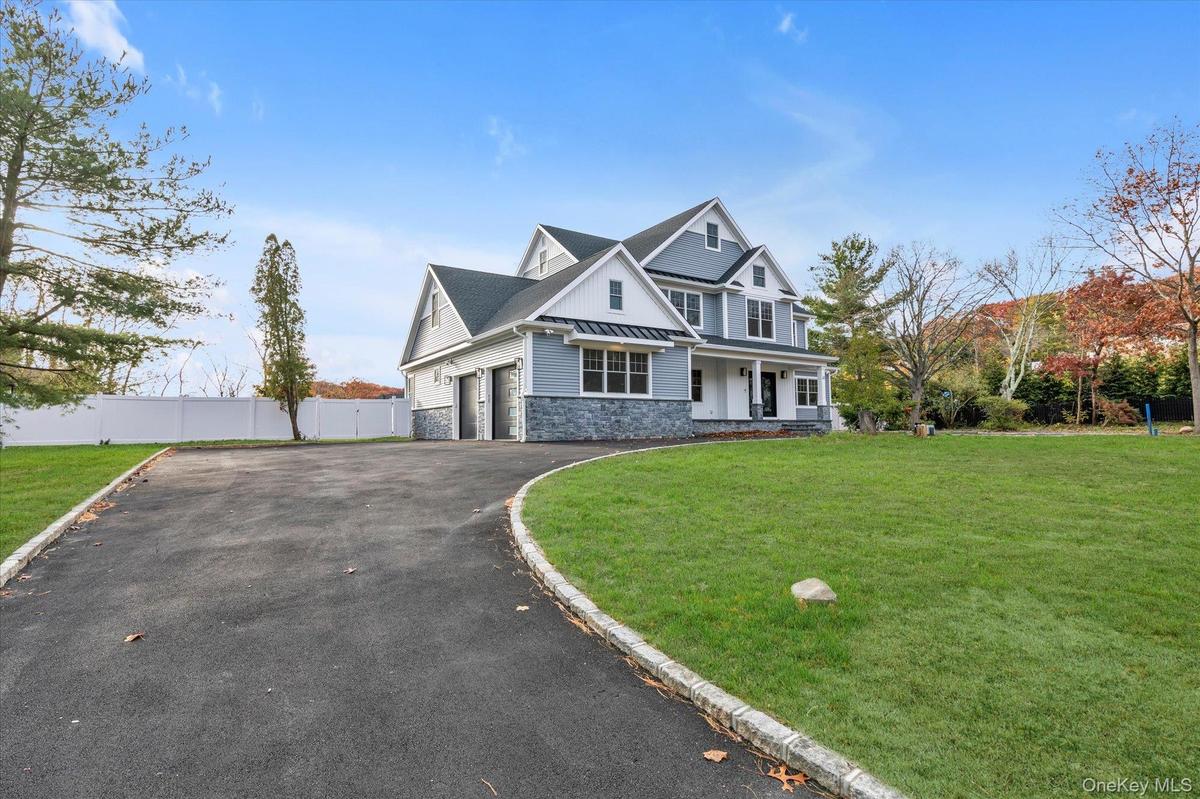 View of front of house featuring stone siding, driveway, and a porch
