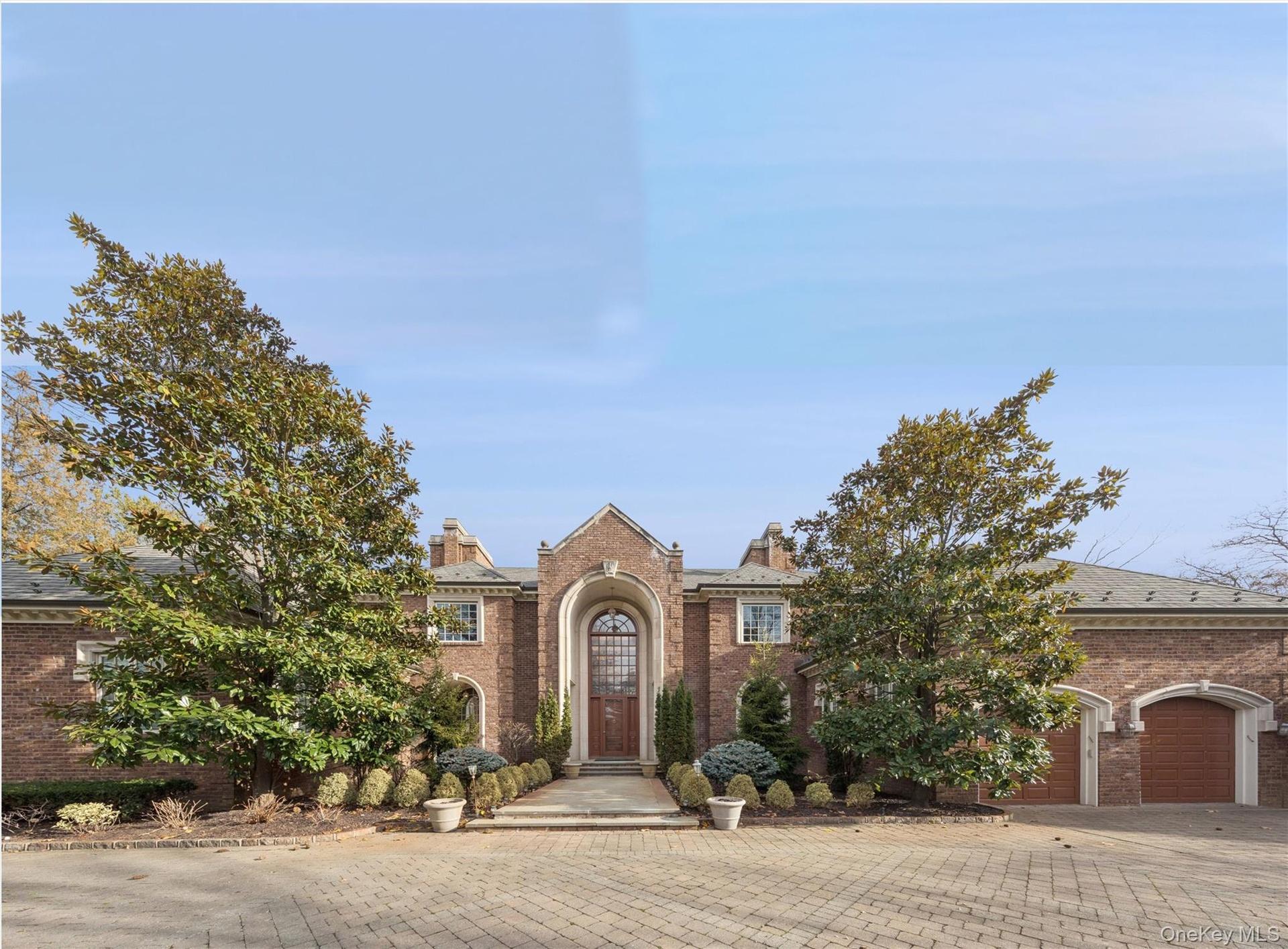 View of front of home with brick siding, driveway, a chimney, and a garage