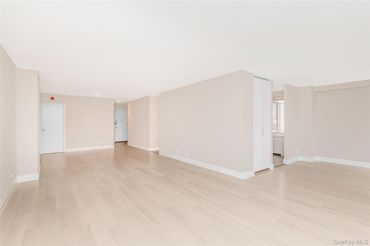 Unfurnished room featuring light wood finished floors and baseboards