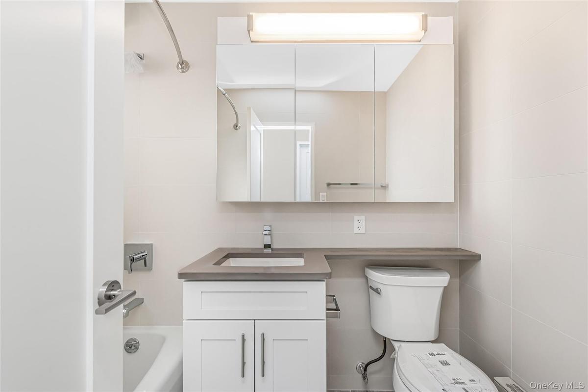 Full bath with vanity, washtub / shower combination, and tile walls