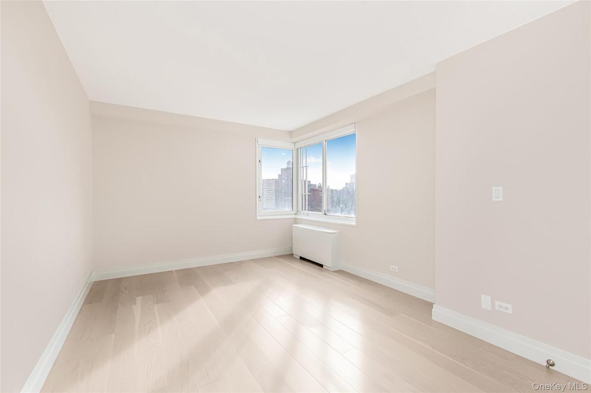 Unfurnished room with radiator heating unit, light wood-style flooring, and a view of city
