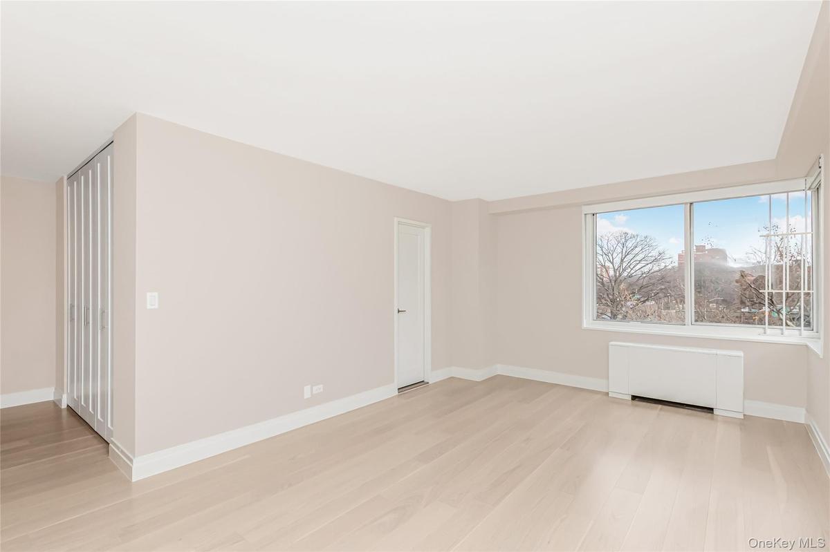 Unfurnished room with radiator heating unit and light wood-style flooring