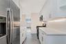 Kitchen with stainless steel appliances, white cabinetry, and light stone countertops