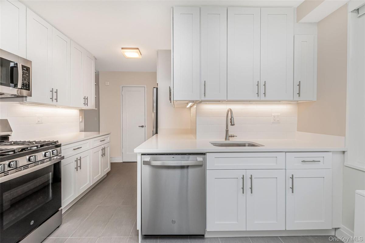 Kitchen featuring stainless steel appliances, tasteful backsplash, and white cabinetry