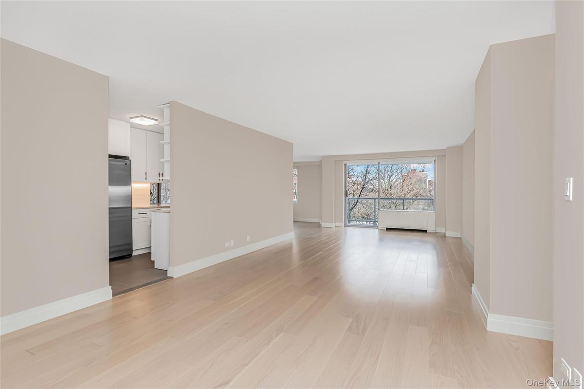 Unfurnished living room featuring light wood-type flooring and baseboards