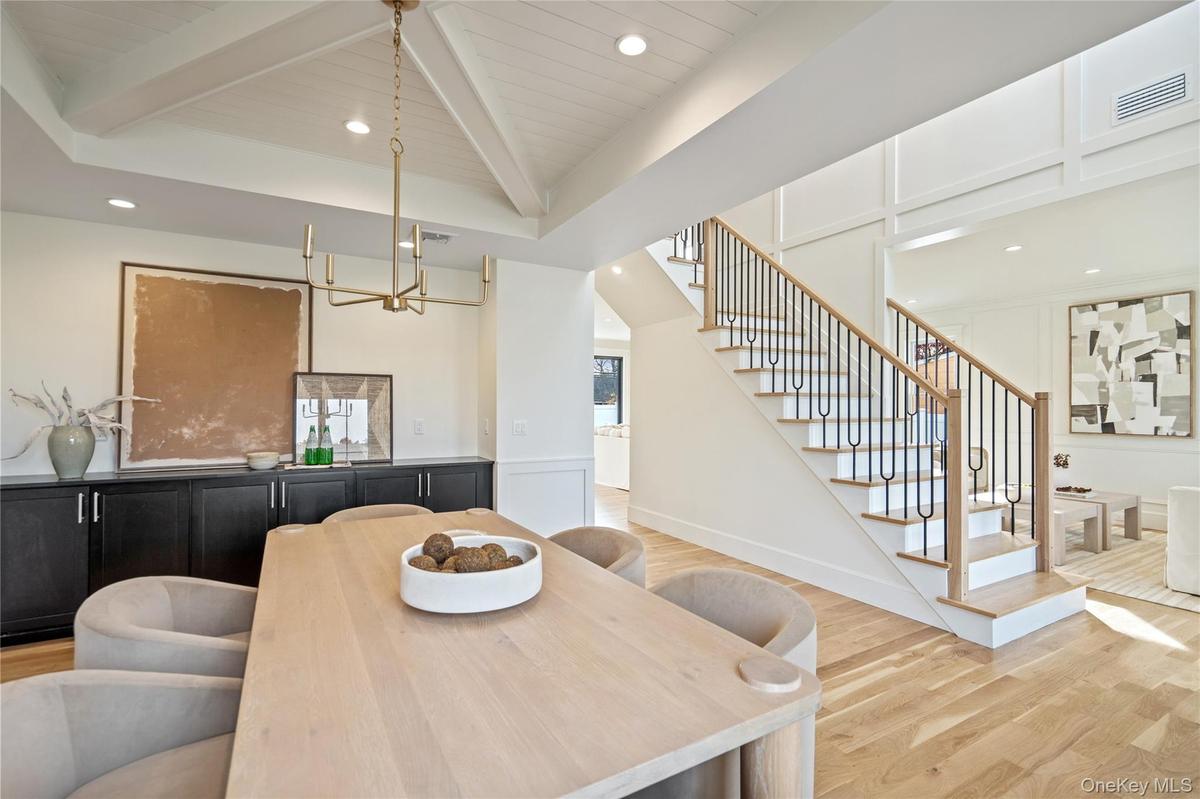 Dining room with beam ceiling, light wood finished floors, stairway, a chandelier, and recessed lighting