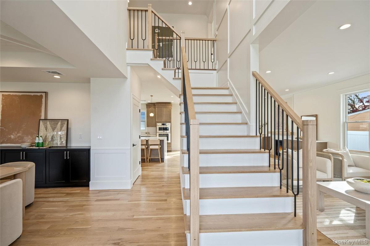 Staircase featuring a decorative wall, wood finished floors, wainscoting, recessed lighting, and a high ceiling
